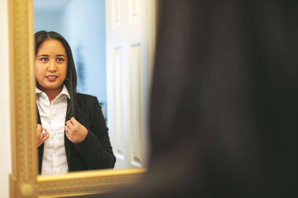 Professional young woman looking in the mirror.