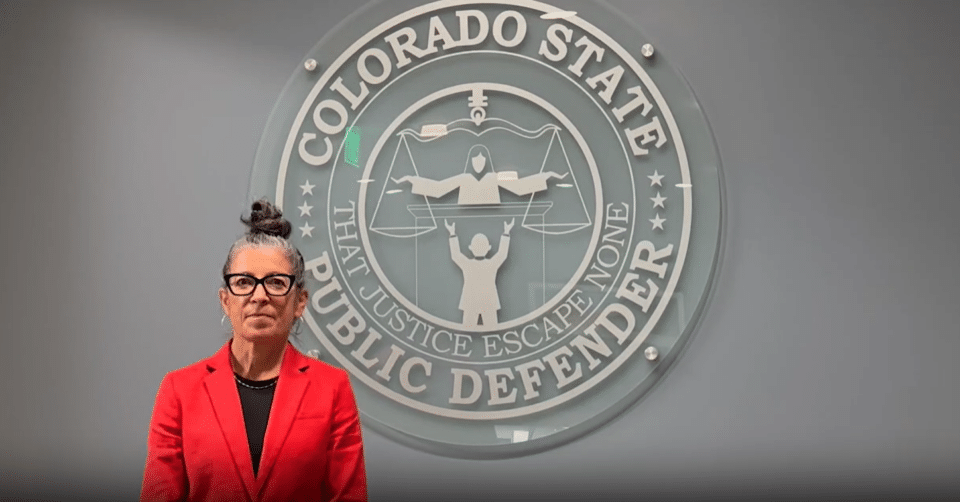 The Public Defender, Megan Ring, standing in front of the OSPD Seal